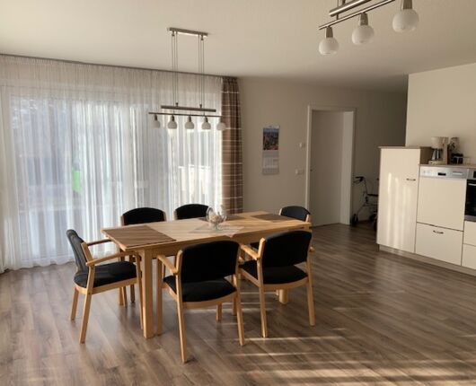 Heller Wohnraum mit Esstisch und Stühlen, symbolisch für das häusliche Umfeld, in dem ambulante Hauskrankenpflege stattfindet.